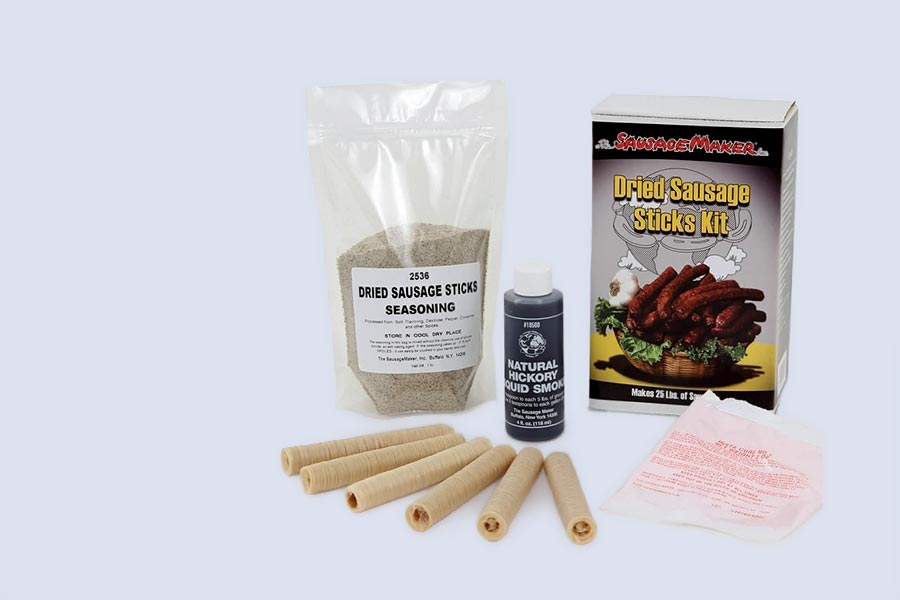 Dried sausage sticks kit with packaging, seasoning, and sticks on a light gray background
