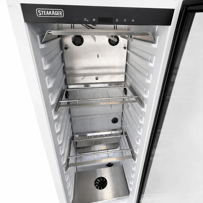 Open Steakager cabinet showing the stainless steel interior with two wire shelves, white crisper compartments, and a black control panel at the top.