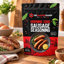 A 1 lb bag of The Sausage Maker Morning Edge Sausage Seasoning stands on a wooden table, with cooked sausage patties, eggs, herbs, and spices arranged around it in a warm kitchen setting.